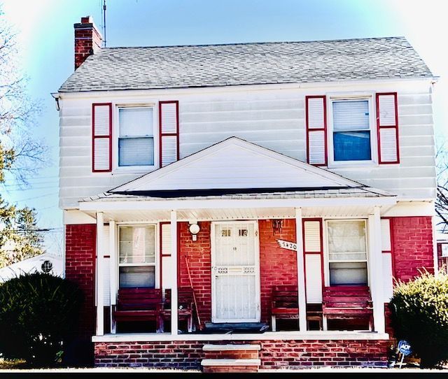 view of front facade featuring a porch, a chimney, and a shingled roof