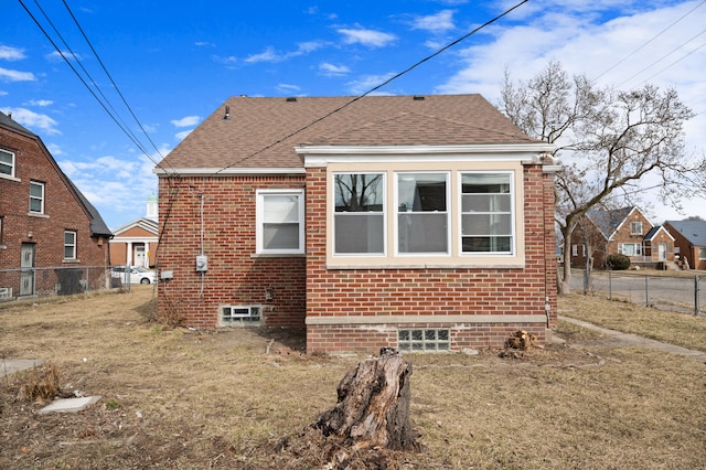 back of house with fence, brick siding, and roof with shingles