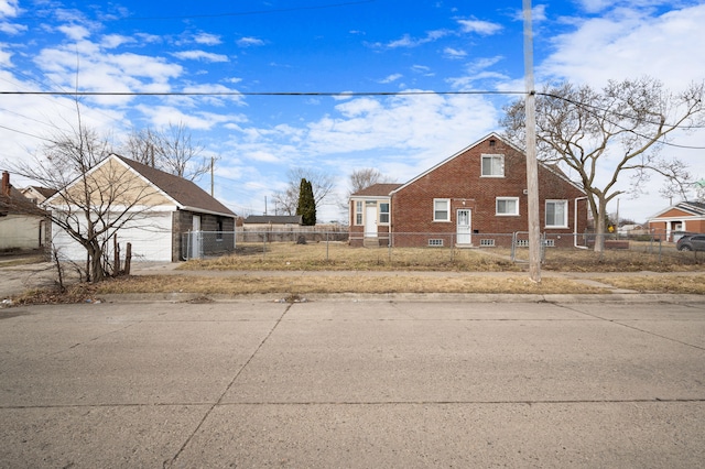 view of home's exterior with a fenced front yard, a detached garage, brick siding, and an outdoor structure