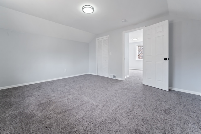 unfurnished bedroom with visible vents, lofted ceiling, carpet, and baseboards