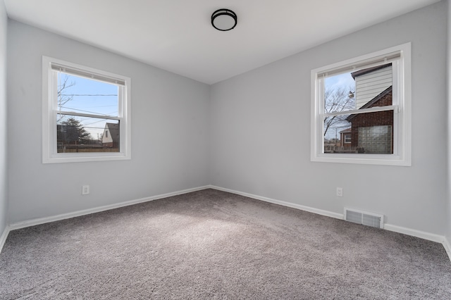 empty room with carpet, visible vents, and baseboards