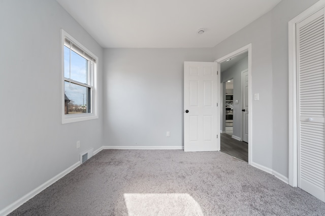 unfurnished bedroom featuring a closet, baseboards, visible vents, and carpet floors