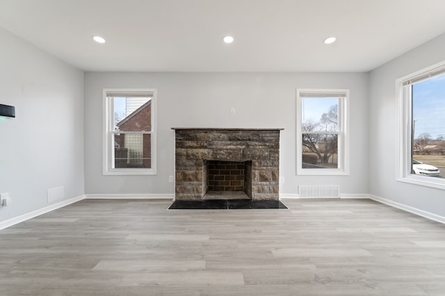 unfurnished living room with a wealth of natural light, visible vents, baseboards, and wood finished floors