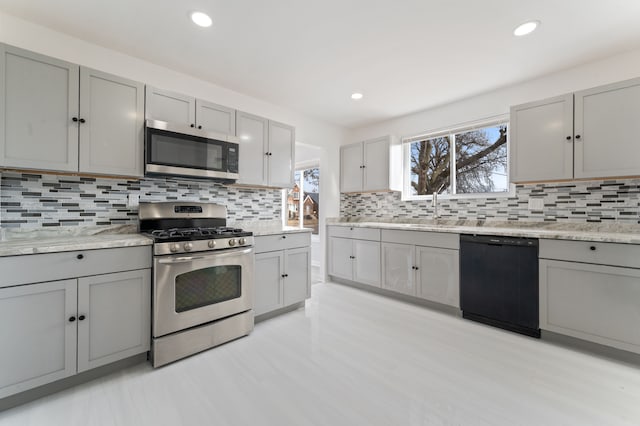 kitchen featuring tasteful backsplash, plenty of natural light, gray cabinets, and appliances with stainless steel finishes