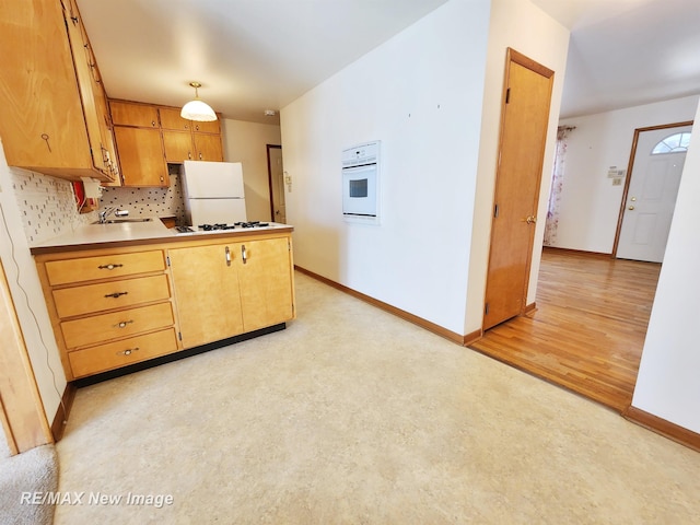 kitchen with a sink, decorative backsplash, white appliances, and baseboards