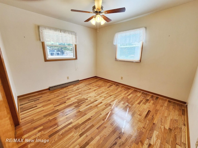 empty room with a wealth of natural light, baseboard heating, and light wood-style flooring