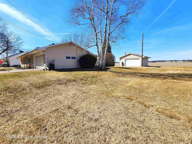 view of side of home featuring a garage, a lawn, and an outdoor structure