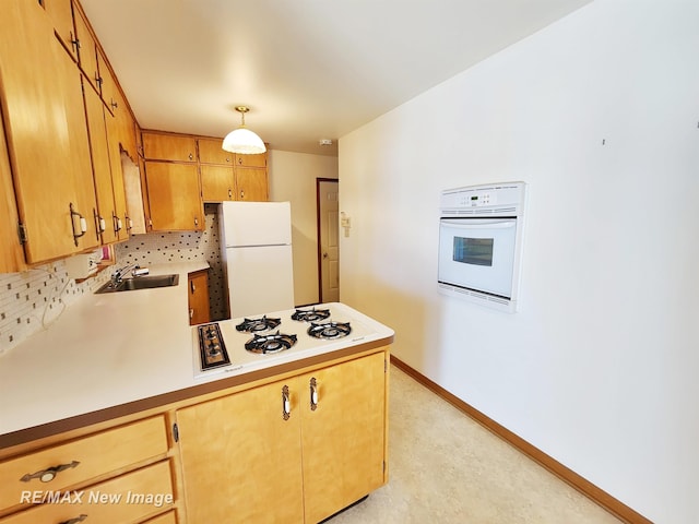 kitchen with white appliances, baseboards, a peninsula, a sink, and light countertops