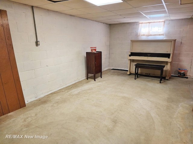 basement with concrete block wall and a paneled ceiling