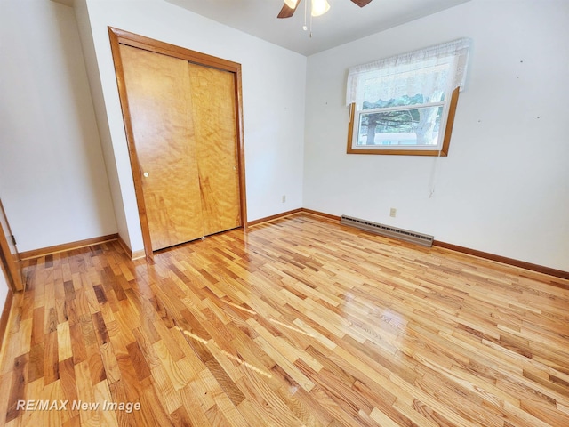 unfurnished bedroom featuring a baseboard heating unit, baseboards, light wood-type flooring, and ceiling fan