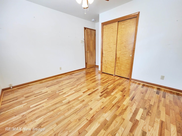 unfurnished bedroom with a closet, light wood-style flooring, baseboards, and ceiling fan