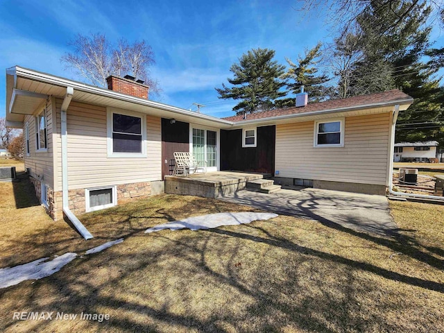 rear view of property with a yard, a chimney, and a patio area