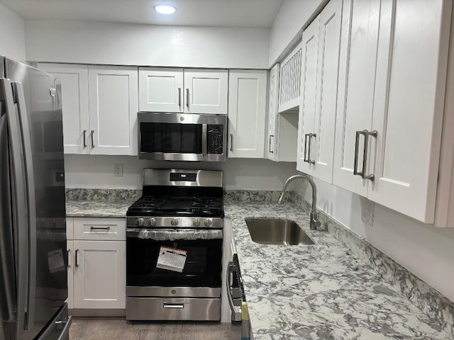 kitchen featuring a sink, light stone counters, white cabinetry, and stainless steel appliances