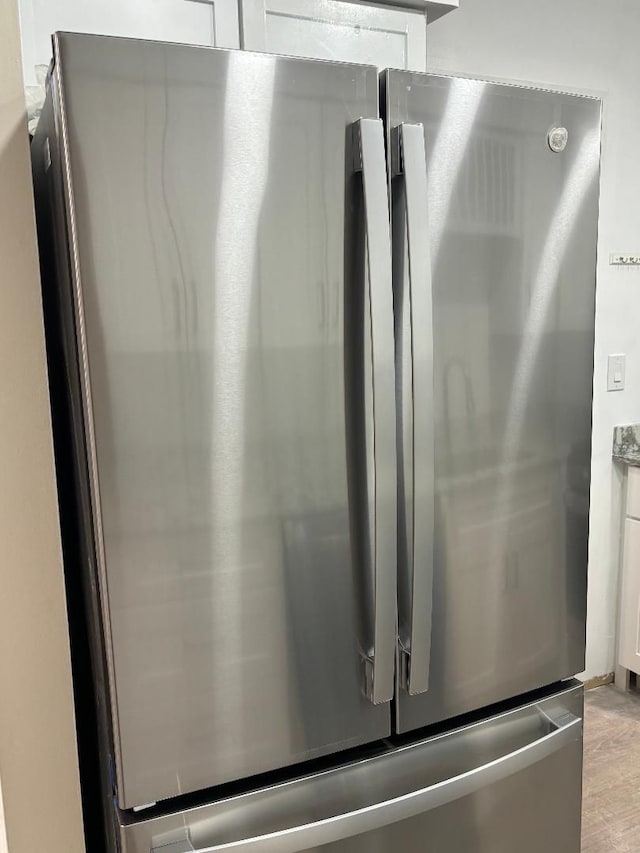 room details featuring white cabinetry, light stone countertops, and freestanding refrigerator