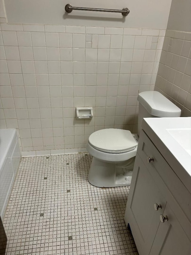 full bathroom featuring tile patterned flooring, vanity, toilet, and tile walls