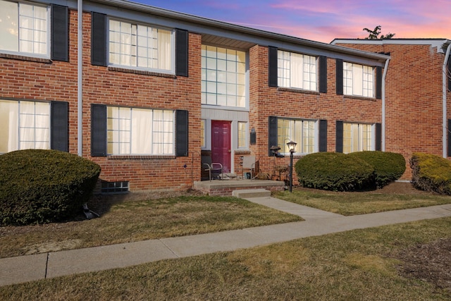 view of property featuring a yard and brick siding