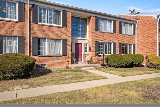 view of property with brick siding and a front yard