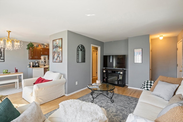 living room with a notable chandelier, light wood-style flooring, and baseboards