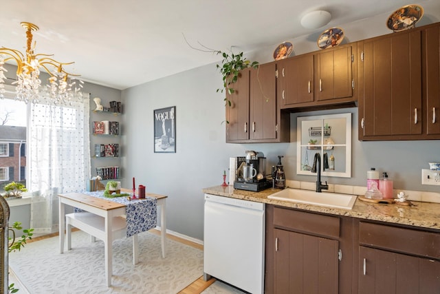 kitchen featuring a sink, baseboards, a chandelier, and white dishwasher