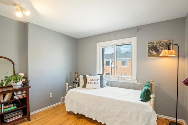 bedroom featuring visible vents, light wood-style floors, and baseboards