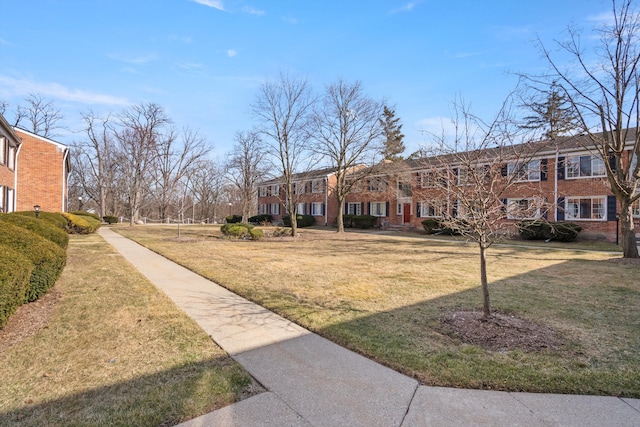 exterior space with brick siding and a front yard