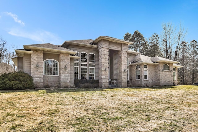 view of front of house with a front lawn, brick siding, and roof with shingles