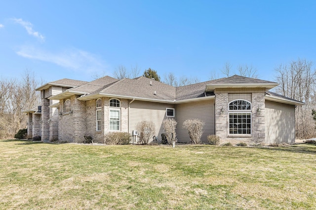 exterior space with a front yard, brick siding, and a shingled roof