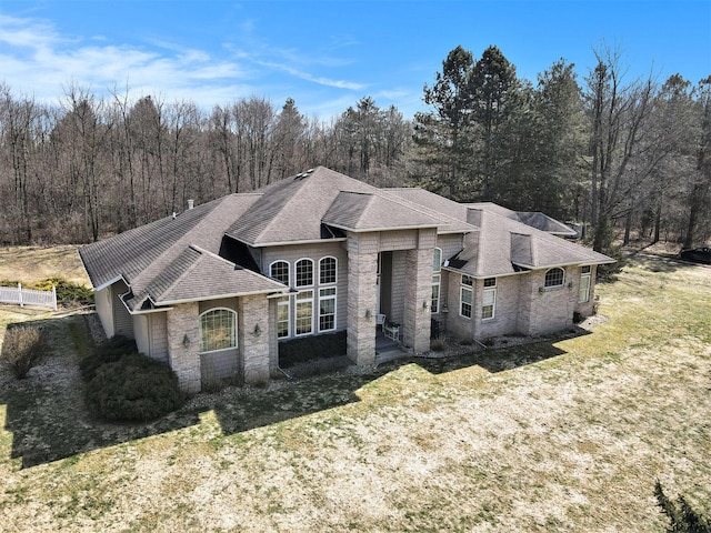 french provincial home with a front yard and roof with shingles