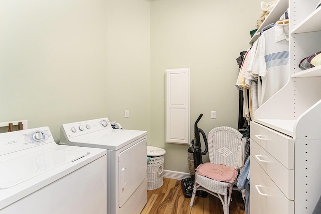 clothes washing area featuring baseboards, light wood-style floors, independent washer and dryer, and laundry area