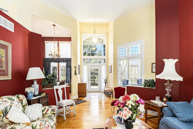 living room with a healthy amount of sunlight, wood finished floors, visible vents, and a chandelier