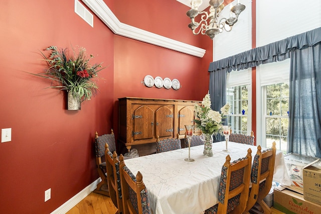 dining space featuring wood finished floors, visible vents, baseboards, and a chandelier