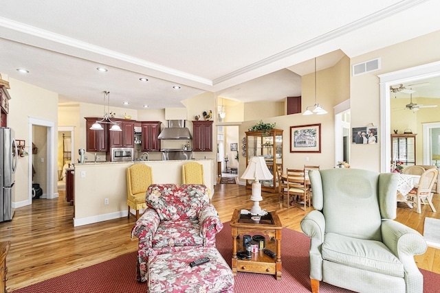 living room featuring light wood finished floors, visible vents, baseboards, and a ceiling fan