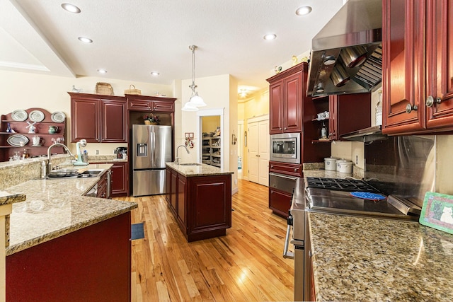 kitchen featuring ventilation hood, an island with sink, stainless steel appliances, dark brown cabinets, and light wood-style floors