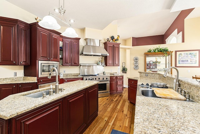 kitchen featuring a sink, reddish brown cabinets, appliances with stainless steel finishes, and wall chimney range hood