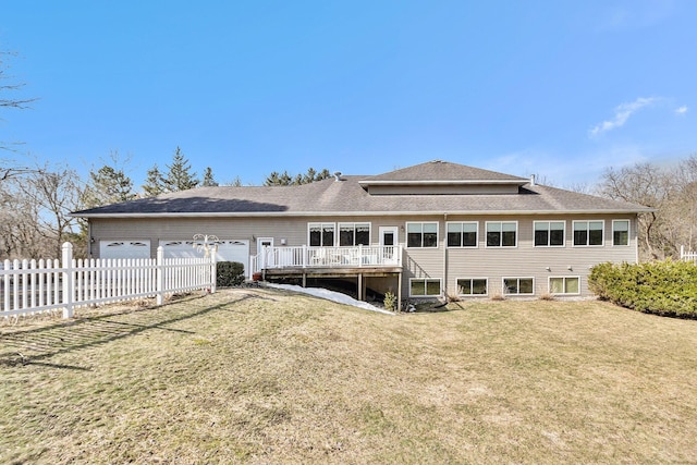 back of property with a garage, a deck, a yard, and fence