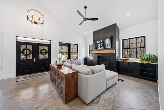 living area featuring high vaulted ceiling, recessed lighting, finished concrete floors, ceiling fan with notable chandelier, and a large fireplace