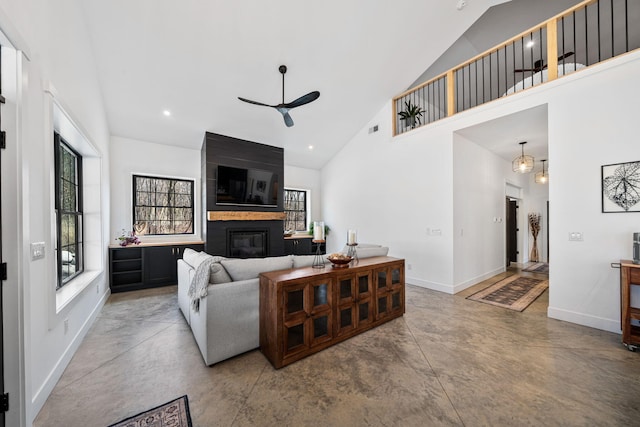 living area featuring high vaulted ceiling, a ceiling fan, finished concrete floors, a fireplace, and baseboards