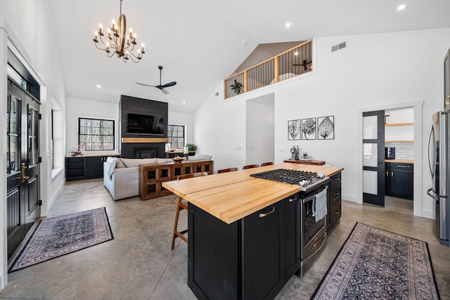 kitchen with visible vents, ceiling fan with notable chandelier, wood counters, stainless steel appliances, and dark cabinets