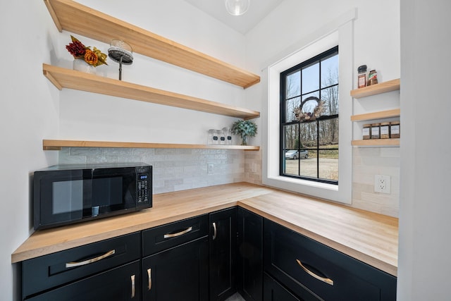 kitchen with open shelves, dark cabinets, black microwave, and butcher block countertops