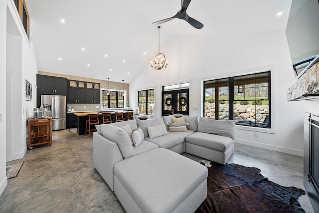 living area featuring high vaulted ceiling, ceiling fan with notable chandelier, recessed lighting, concrete floors, and baseboards