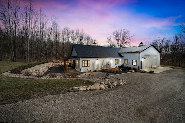 view of front of property featuring metal roof, a garage, covered porch, and driveway