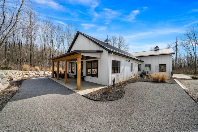 view of property exterior featuring a patio, a chimney, and metal roof