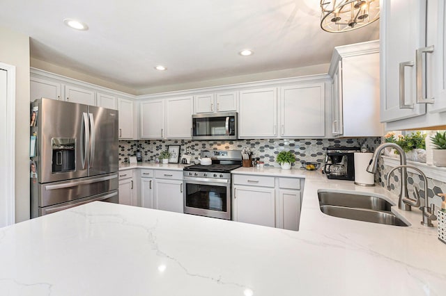 kitchen featuring a notable chandelier, decorative backsplash, stainless steel appliances, and a sink