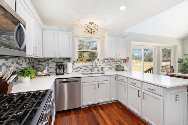 kitchen with a peninsula, light countertops, appliances with stainless steel finishes, and a sink