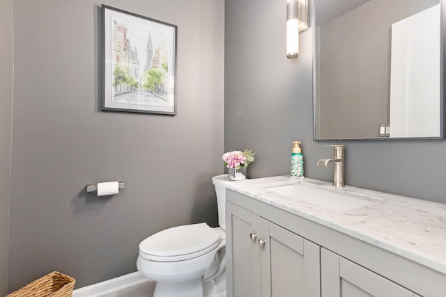 half bath with vanity, toilet, and baseboards