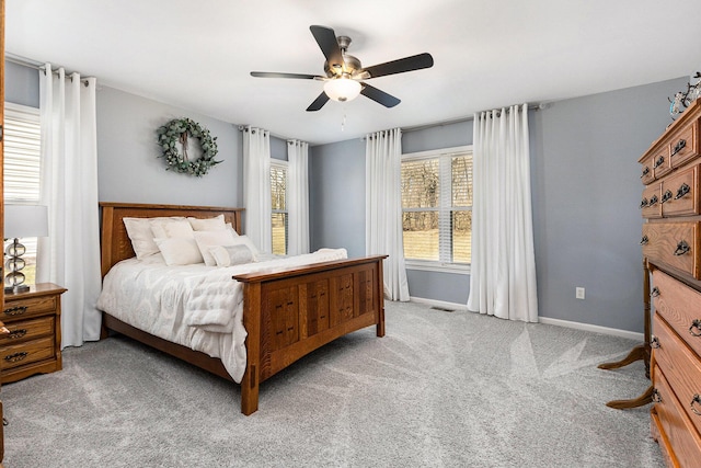 carpeted bedroom featuring multiple windows, baseboards, and ceiling fan