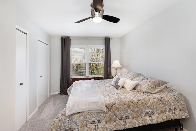 bedroom featuring ceiling fan, baseboards, carpet, and multiple closets