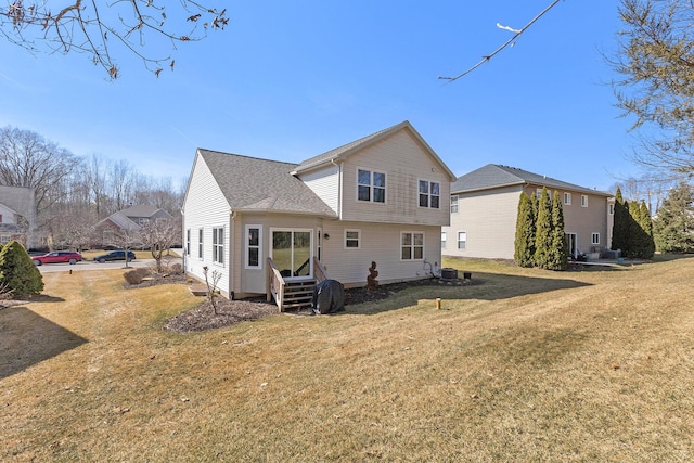 rear view of property featuring entry steps, central AC unit, and a lawn