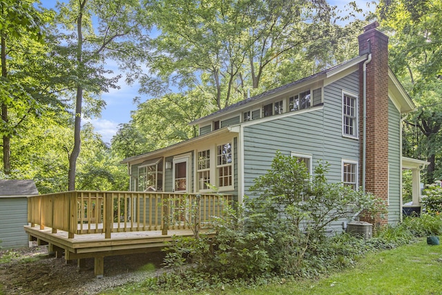 back of house featuring central AC, a chimney, and a deck