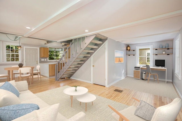 living area with stairs, light wood-style flooring, plenty of natural light, and baseboards